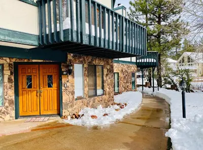 a building with a red door and snow on the ground at Lakefront Viking Oasis - Beautiful Viking Estates condo complex on the lake! in Big Bear Lake