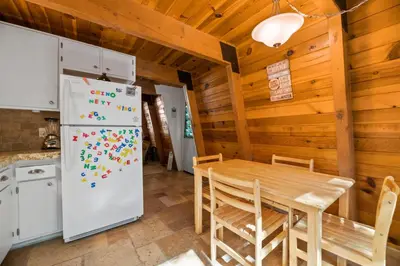 a kitchen and dining room with a table and refrigerator at A Beary Happy Cabin - Charming gambrel style home within minutes of the Lake and The Village in Big Bear Lake