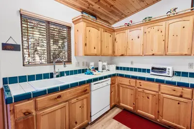 a kitchen with wooden cabinets and a white dishwasher at McWhinney The Pooh's Den - Everything you need for a memorable time with family! Pool Table! in Big Bear Lake