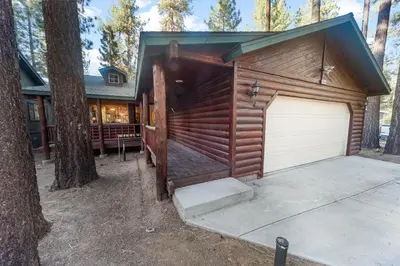 a building with a garage in the middle of a forest at McWhinney The Pooh's Den - Everything you need for a memorable time with family! Pool Table! in Big Bear Lake