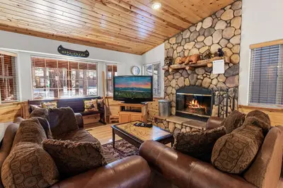a living room with leather furniture and a stone fireplace at McWhinney The Pooh's Den - Everything you need for a memorable time with family! Pool Table! in Big Bear Lake
