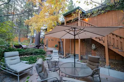 a patio with a table and chairs and an umbrella at Treetop Bearadise - Best mountain living in a nicely furnished and decorated home in Big Bear Lake