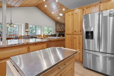 a kitchen with wooden cabinets and a stainless steel refrigerator at Treetop Bearadise - Best mountain living in a nicely furnished and decorated home in Big Bear Lake
