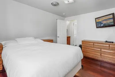 a bedroom with a white bed and a wooden dresser at The Rock House - Walk to Big Bear Snow Play! Walk to Oktoberfest! Perfect weekend getaway! in Big Bear City