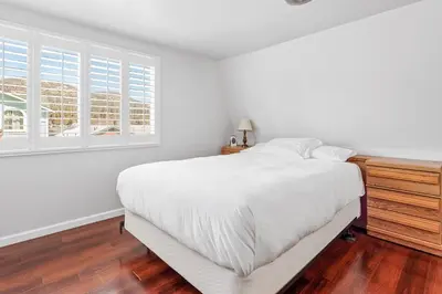 a white bedroom with a large bed and windows at The Rock House - Walk to Big Bear Snow Play! Walk to Oktoberfest! Perfect weekend getaway! in Big Bear City