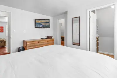 a white bedroom with a large bed and two windows at The Rock House - Walk to Big Bear Snow Play! Walk to Oktoberfest! Perfect weekend getaway! in Big Bear City