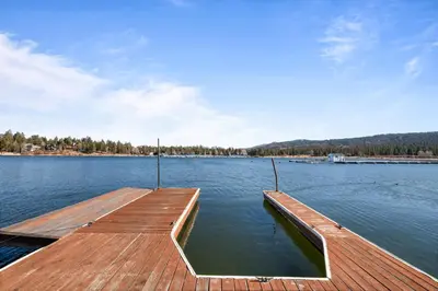 a dock in the middle of a body of water at The Voges' Lake House - Amazing lake front house with a beautiful view and game room! in Big Bear Lake