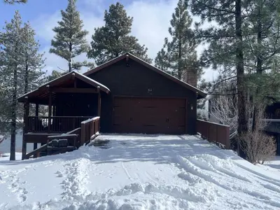 a building with a garage in the snow at The Voges' Lake House - Amazing lake front house with a beautiful view and game room! in Big Bear Lake