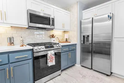 a kitchen with blue cabinets and a stainless steel refrigerator at The Grizzlies Den - Log style cabin located in the desirable Fox Farm area! Games and arcade! in Big Bear Lake