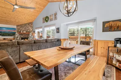 a dining room with a wooden table and a couch at The Grizzlies Den - Log style cabin located in the desirable Fox Farm area! Games and arcade! in Big Bear Lake