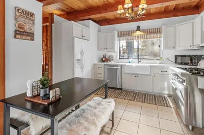 a kitchen with white cabinets and a black table at The Lakehouse Cabin - Located close to the Lake! Hot Tub, Smart TV, and WiFi! in Big Bear Lake