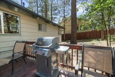 a grill on a deck next to a house at The Oasis Chalet - Walking distance to The Village, The Lake, and Alpine Slide! in Big Bear Lake