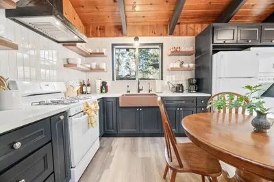 a kitchen with blue cabinets and a wooden table at The Oasis Chalet - Walking distance to The Village, The Lake, and Alpine Slide! in Big Bear Lake