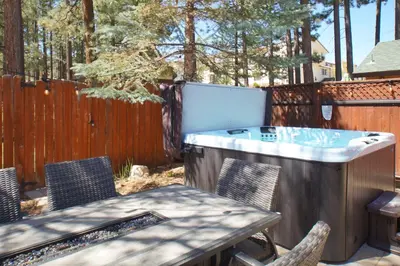a hot tub in a backyard with a table and chairs at The Bear Den - DREAM LOCATION WALKING DISTANCE TO LAKE AND VILLAGE! in Big Bear Lake