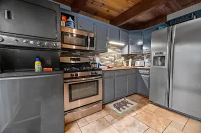 a kitchen with stainless steel appliances and blue cabinets at The Cozy Bear Cabin - Updated gambrel with huge outdoor space! Cornhole, Tether ball, Fire pit! in Big Bear Lake