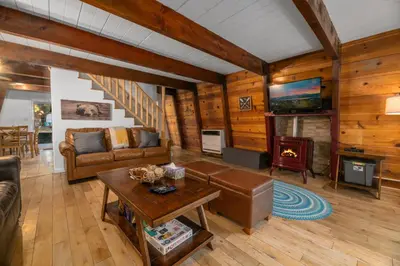 a living room with a couch and a fireplace at The Cozy Bear Cabin - Updated gambrel with huge outdoor space! Cornhole, Tether ball, Fire pit! in Big Bear Lake