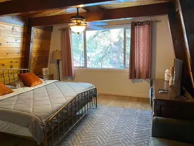 a bedroom with a bed and a large window at The Cozy Bear Cabin - Updated gambrel with huge outdoor space! Cornhole, Tether ball, Fire pit! in Big Bear Lake