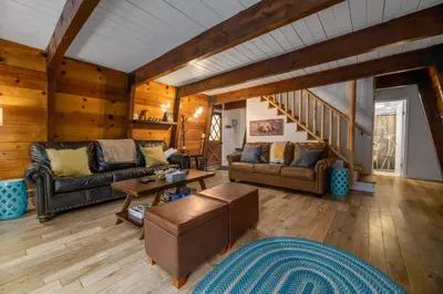 a living room with leather furniture and wooden walls at The Cozy Bear Cabin - Updated gambrel with huge outdoor space! Cornhole, Tether ball, Fire pit! in Big Bear Lake