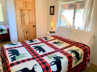 a bedroom with a bed with a checkered blanket at The Fox Paw - Cozy and spacious cabin! Family game room with Foosball and Pool Table! Jet Tub! in Big Bear Lake