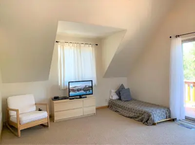a bedroom with a bed and a tv and a chair at The Fox Paw - Cozy and spacious cabin! Family game room with Foosball and Pool Table! Jet Tub! in Big Bear Lake