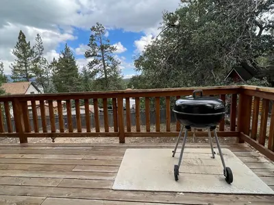 a grill sitting on a wooden deck on a porch at The Fox Paw - Cozy and spacious cabin! Family game room with Foosball and Pool Table! Jet Tub! in Big Bear Lake