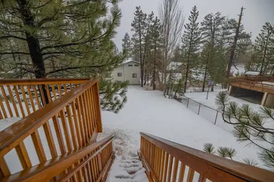a snow covered yard with a house and trees at Sweet Retreat - Spectacular little hideaway, cozy family getaway near the lake! in Big Bear Lake