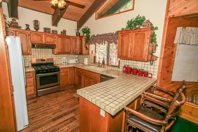a kitchen with wooden cabinets and a counter top at Summit Adventure - Beautiful, spacious and quiet home! Foosball, pool and poker table! Jet tub! in Big Bear Lake