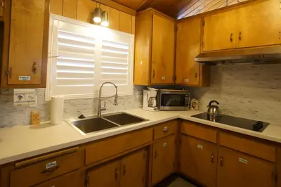 a kitchen with wooden cabinets and a sink and a microwave at Snowridge - Charming classic cabin with a wood burning fireplace and WiFI! in Big Bear City
