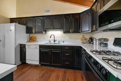 a kitchen with black cabinets and white appliances at Bare Necessities - Comes with a hot tub and a pool table in Big Bear Lake