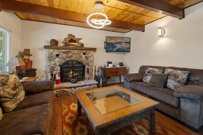 a living room with couches and a stone fireplace at Bare Necessities - Comes with a hot tub and a pool table in Big Bear Lake