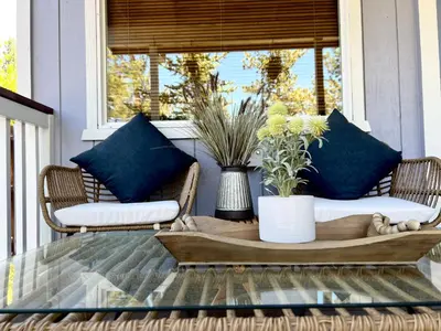 a porch with two wicker chairs and a table at Serenity Knoll - Comfortable, spacious single-level cabin! Newly remodeled! Hot Tub and Pool Table! in Big Bear Lake