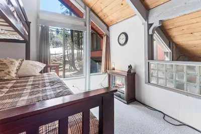 a bedroom with a bed and a fireplace at Ski-In Ski-Out Summit Townhouse- Perfect mountain getaway with views of the forest and Snow Summit! in Big Bear Lake