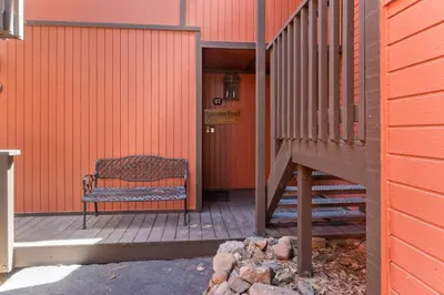 a bench sitting on a porch next to a building at Ski-In Ski-Out Summit Townhouse- Perfect mountain getaway with views of the forest and Snow Summit! in Big Bear Lake