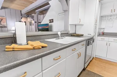 a kitchen with white cabinets and a sink at Ski-In Ski-Out Summit Townhouse- Perfect mountain getaway with views of the forest and Snow Summit! in Big Bear Lake