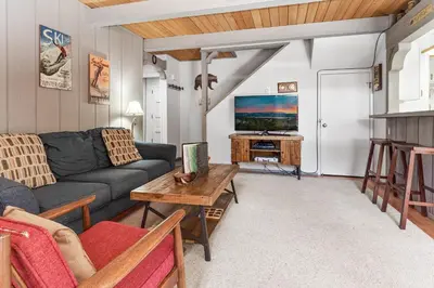 a living room with a couch and a tv at Ski-In Ski-Out Summit Townhouse- Perfect mountain getaway with views of the forest and Snow Summit! in Big Bear Lake