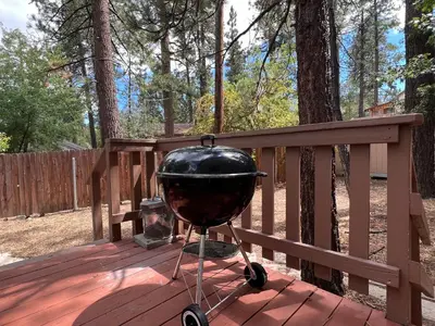 a grill sitting on a deck on a porch at Rincon Cabin - Close to the lake with a huge fenced in yard! Hot tub and deck with barbecue! in Big Bear Lake