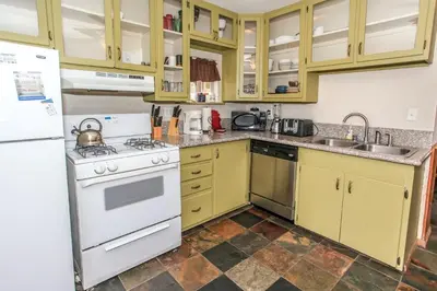 a kitchen with yellow cabinets and white appliances at Rincon Cabin - Close to the lake with a huge fenced in yard! Hot tub and deck with barbecue! in Big Bear Lake