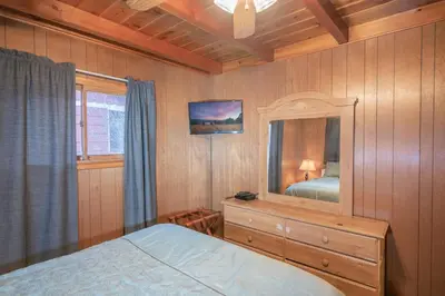 a bedroom with a bed and a dresser and a mirror at Sauer Suite - Cozy, rustic cabin walking distance to Holloway's Marina with peek-a-boo lake views! in Big Bear Lake
