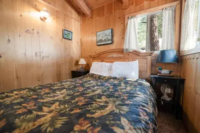a bedroom with a bed in a wooden room at Owl Cabin - Sierra style cabin located on a quiet road in Fawnskin and backs up to National Forest! in Fawnskin
