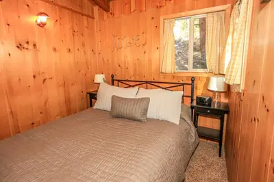 a bedroom with a bed in a wooden room at Owl Cabin - Sierra style cabin located on a quiet road in Fawnskin and backs up to National Forest! in Fawnskin