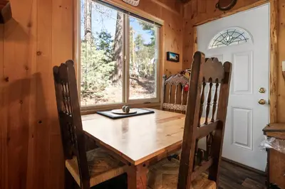 a dining room with a table and chairs and a window at Owl Cabin - Sierra style cabin located on a quiet road in Fawnskin and backs up to National Forest! in Fawnskin