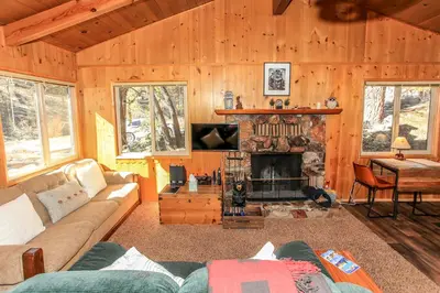 a living room with a couch and a fireplace at Owl Cabin - Sierra style cabin located on a quiet road in Fawnskin and backs up to National Forest! in Fawnskin