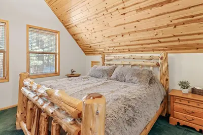 a bedroom with a wooden bed and a wooden ceiling at Papa Bear's Hideout - Dream Getaway with Hot Tub and Game Room! in Big Bear Lake