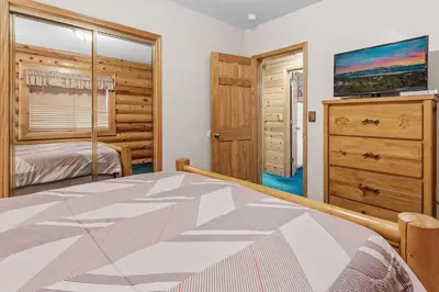 a bedroom with a bed and a dresser and a television at Papa Bear's Hideout - Dream Getaway with Hot Tub and Game Room! in Big Bear Lake