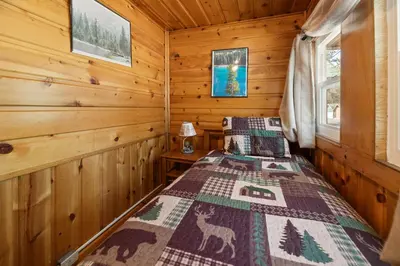 a bedroom with a bed in a log cabin at Pine Forest Cabin - Adorable vintage cabin with a cozy wood burning fireplace and foosball table! in Big Bear Lake