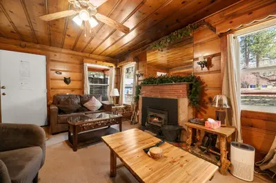 a living room with a fireplace in a log cabin at Pine Forest Cabin - Adorable vintage cabin with a cozy wood burning fireplace and foosball table! in Big Bear Lake