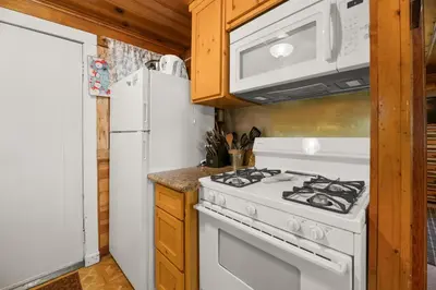 a kitchen with a white stove and a refrigerator at Pine Forest Cabin - Adorable vintage cabin with a cozy wood burning fireplace and foosball table! in Big Bear Lake