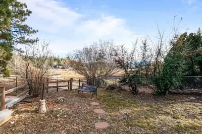 a park bench sitting in a yard next to a fence at North Shore Lakefront - Spacious Lakefront with Hot Tub, & Game Room in Fawnskin