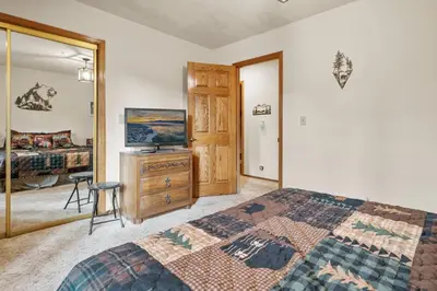 a bedroom with a bed and a dresser and a mirror at North Shore Lakefront - Spacious Lakefront with Hot Tub, & Game Room in Fawnskin