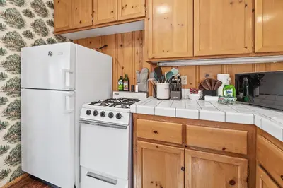 a kitchen with white appliances and wooden cabinets at Oak Nesting - Great chalet style cabin at the end of the street with rustic stone gas log fireplace! in Big Bear Lake